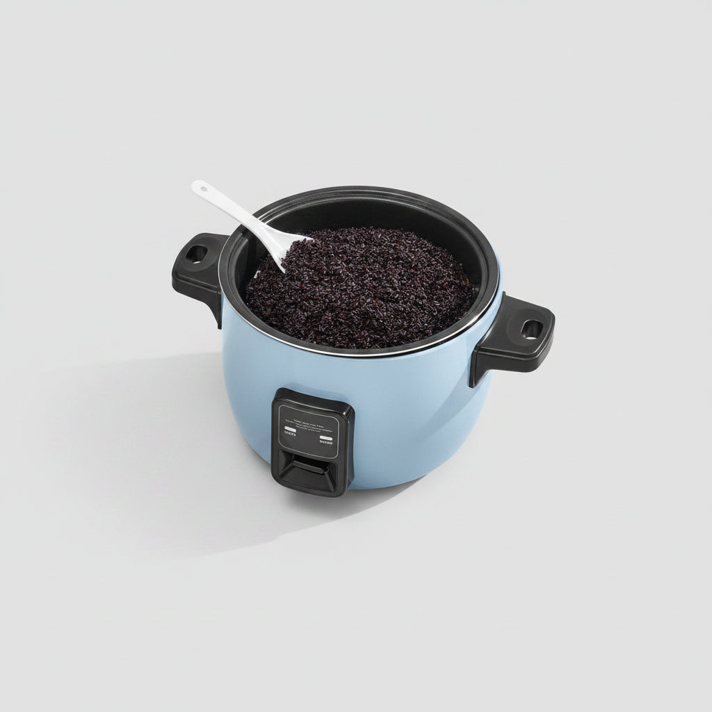 Person adding ingredients to a blue rice cooker on a marble countertop.